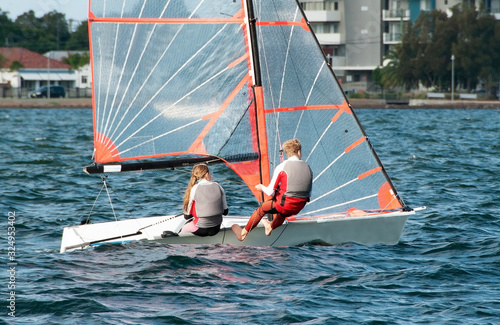 High school students Sailing small sailboat in competition on a saltwater lake.