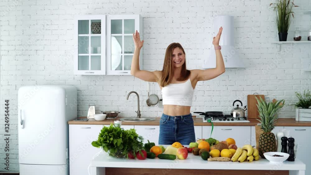 The girl on the background of the white kitchen near the table with fruits and vegetables throws the measuring tape to the top. Diet for weight loss. The girl on the background of the white kitchen near the table with fruits and vegetables throws the measuring tape to the top. Diet for weight loss.