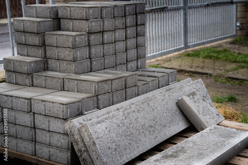 Stack of concrete paving blocks and kerbs on a wooden pallet. Gray concrete slabs for paving a road, driveway or patio