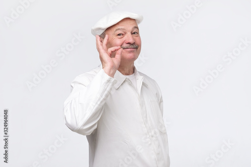 Cooking, food, profession and gesture concept. Smiling senior male chef showing sign ok. Professional male chef in white uniform gesturing excellent. Studio shot