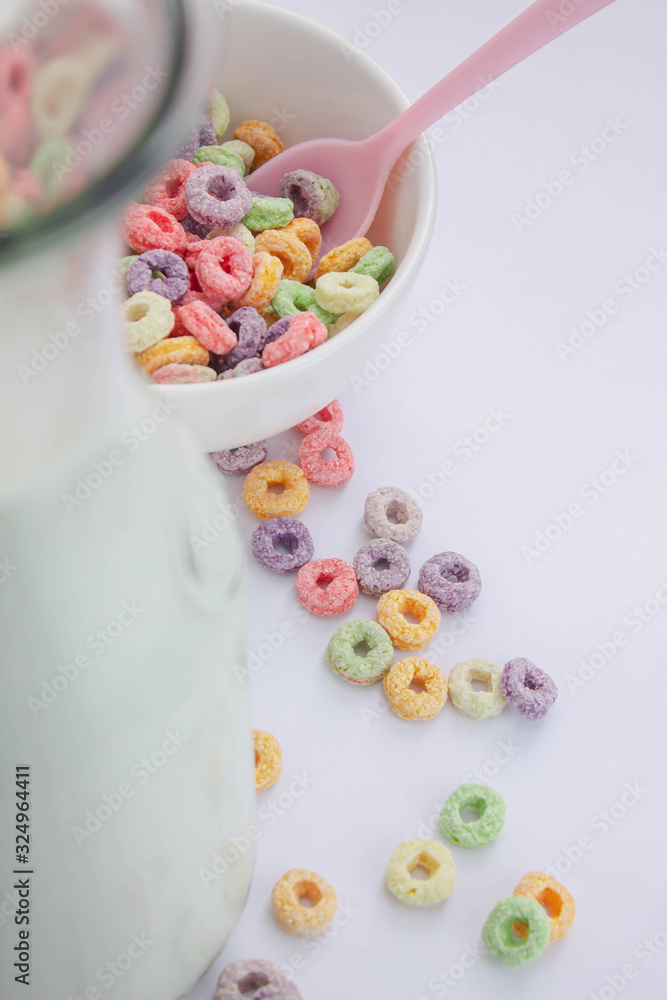 Jug of milk next to unfocused fruit cereal Jug of milk next to unfocused fruit cereal
