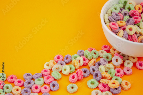 Photo Spilled fruit cereal in white cup on orange texture