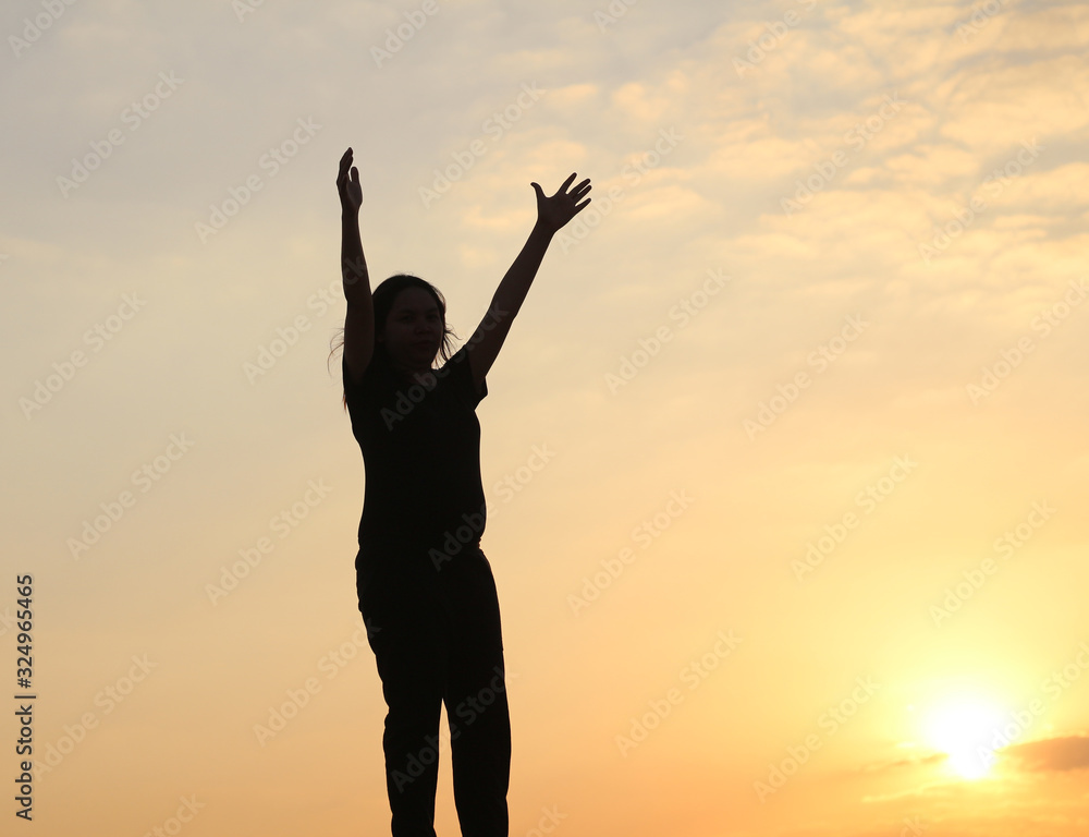 woman silhouette arms up to the sunset feeling happy and freedom.