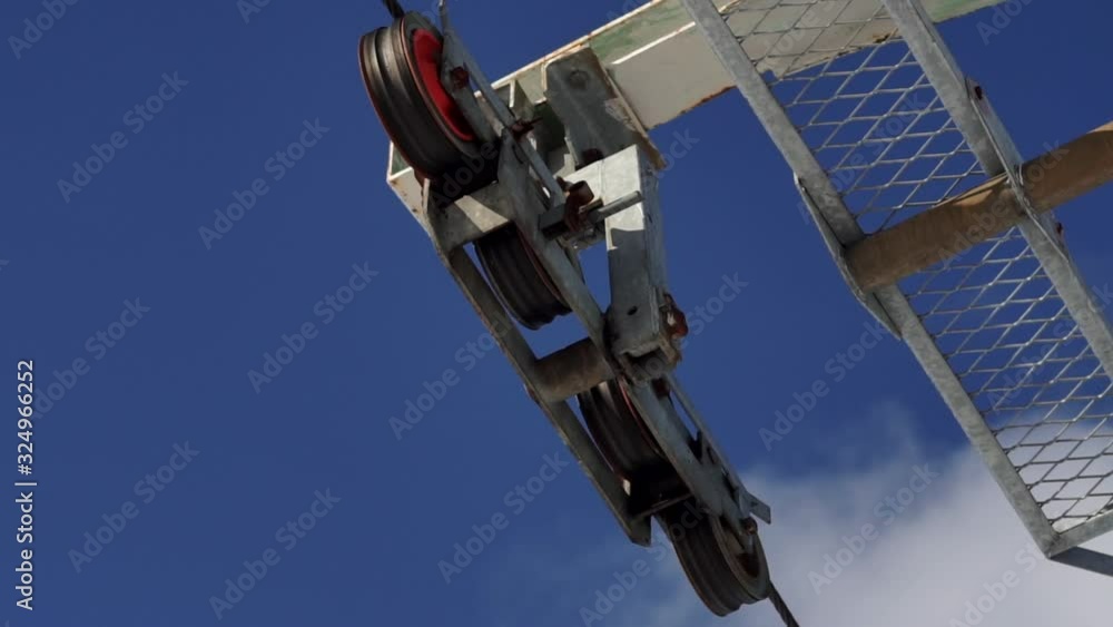 Cable car mechanism with metal rope in working process on a bright winter day. Cableway details on a deep blue sky background, close-up. Cable car mechanism with metal rope in working process on a bright winter day. Cableway details on a deep blue sky background, close-up.