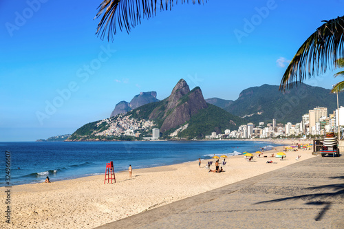 Ipanema beach Rio de Janeiro, Brazil. The sea, the beach, the blue sky and the hill two brothers in the background. Many people in the sand.