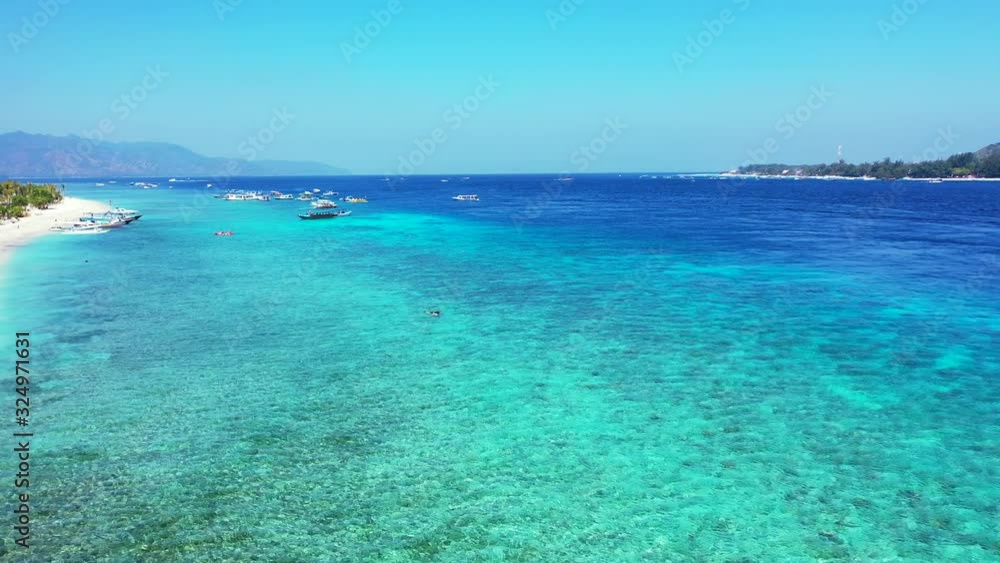 Crystal emerald water of calm turquoise lagoon with boats floating near shore of tropical island with white beach in Indonesia Crystal emerald water of calm turquoise lagoon with boats floating near shore of tropical island with white beach in Indonesia