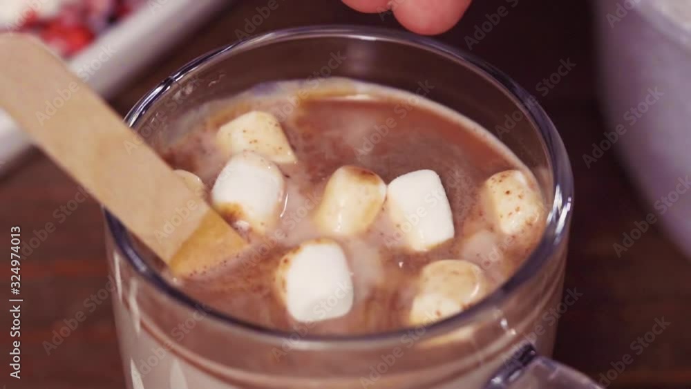 Slow motion. Close up. Salted caramel hot cocoa spoon in glass cup topped with marshmallows. Slow motion. Close up. Salted caramel hot cocoa spoon in glass cup topped with marshmallows.