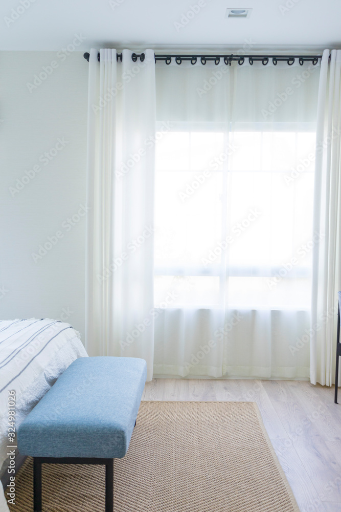 Fototapeta premium Carpet and blue bench near king size bed by the window.