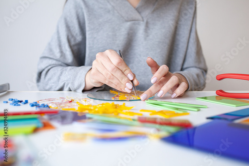 Woman puts out a mosaic of glass with tweezers, fusing, crafting photo