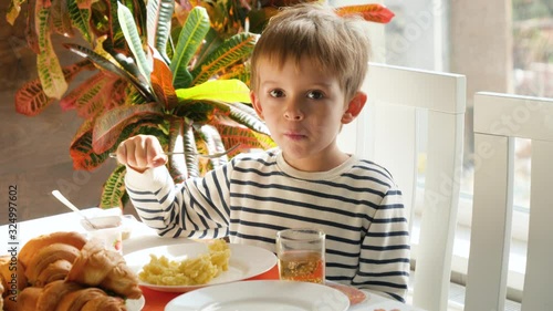 4k video of little 4 years old having lunch in dining room and eating mashed potate with fork photo