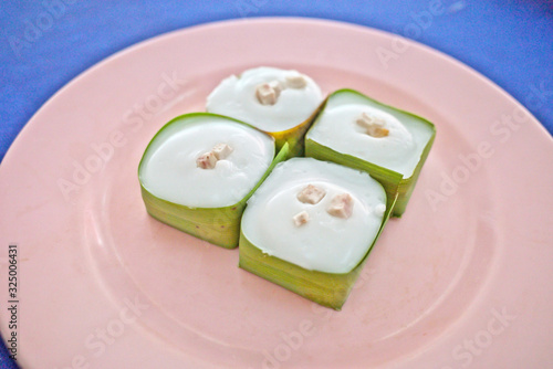 Abstract selective focus of tasty Thai jelly with taro ,creamy coconut topping recipe inside Pandan leaves cube calls Khanom Tako ,which is delicious sweet dessert like pudding with coconut topping photo