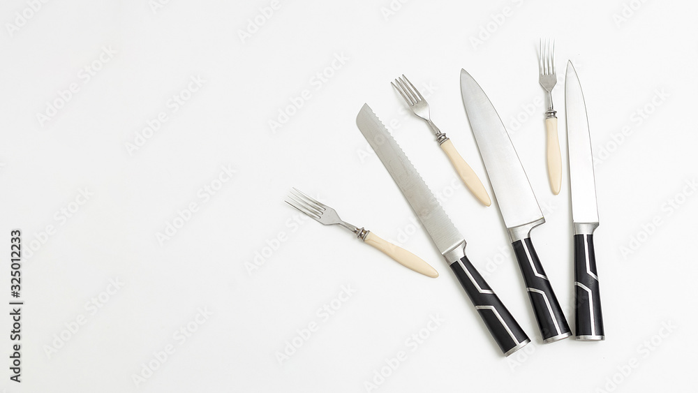 three forks, sharp kitchen knives with black handles isolated on white background. top view on group of tableware with shining metal blades. simple flat lay composition with copyspace. Space for text three forks, sharp kitchen knives with black handles isolated on white background. top view on group of tableware with shining metal blades. simple flat lay composition with copyspace. Space for text