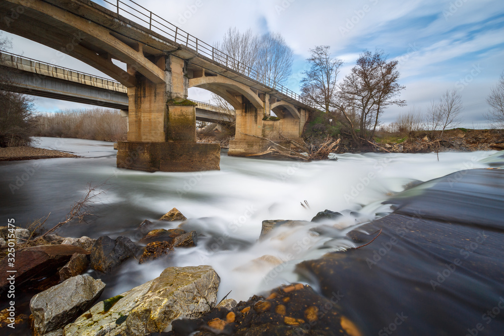 Paisaje con las aguas en movimiento del Río Órbigo y el puente Paulón