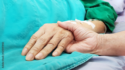 Oncologist doctor holding patient's hand in hospital. Showing all love, empathy, helping and encouragement. He has end stage cancer disease. Healthcare in end of life and palliative care concept photo