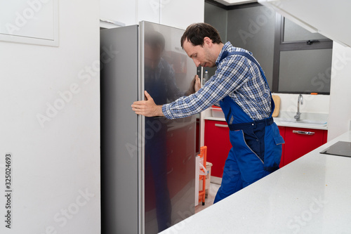 Mover Placing Refrigerator In Kitchen