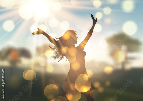 Silhouette of young woman against sunlit defocussed landscape