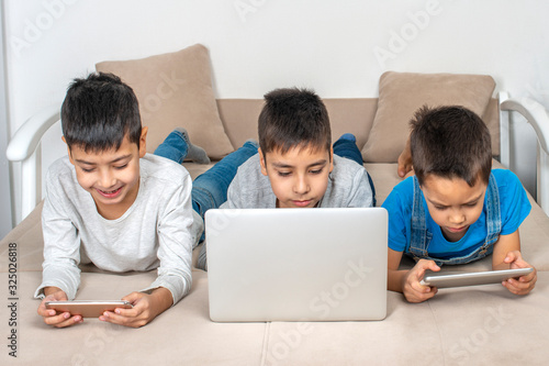Three boys browsing the internrt together on a laptop. Modern lifestyle. © rozaivn58