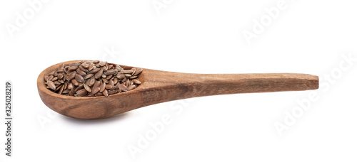 Linseeds or flax seed on a brown wooden spoon seen obliquely from the side and above and isolated on white background