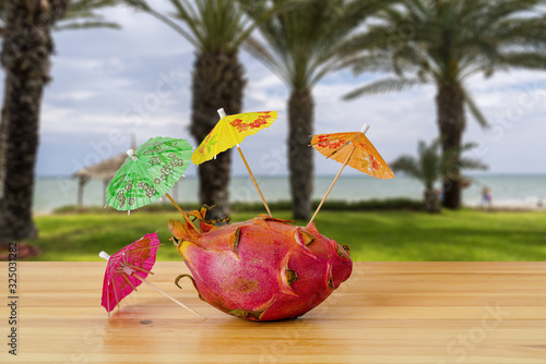 Pitaya  dragon fruit  with cocktail umbrellas on a tropical background