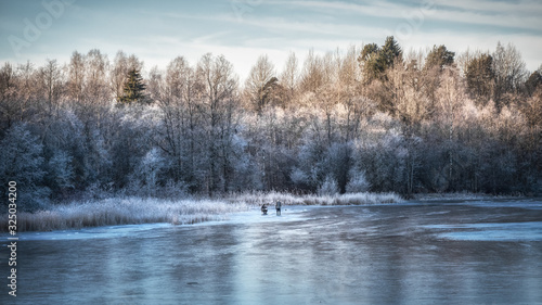 Beautiful winter day with ice fishing. Panorama of a winter landscape with a frozen lake and white trees in the frost