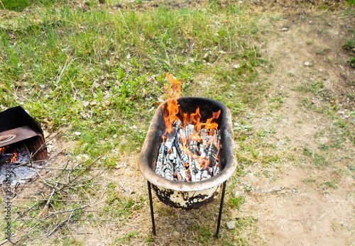 Seasonal outdoor activities, barbecue meat close-up. Marinated kebab is grilled on charcoal. Next is a stove with burning wood