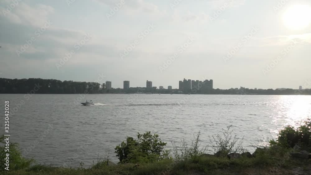 Speedboat is sailing on river in front of cityscape Speedboat is sailing on river in front of cityscape