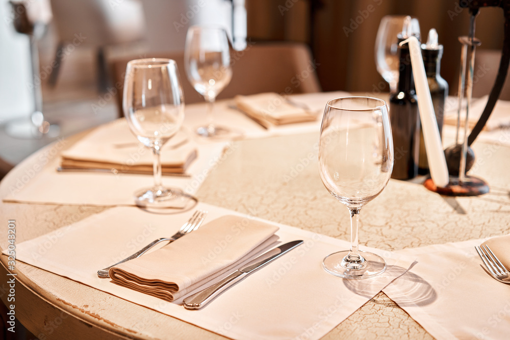 Wine glasses in the foreground. The chairs and table for guests, served with cutlery and crockery Wine glasses in the foreground. The chairs and table for guests, served with cutlery and crockery