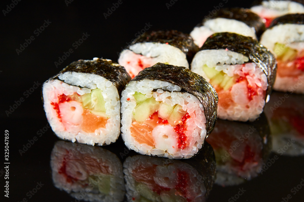 Traditional sushi roll with salmon, cream cheese, shrimp and cucumber on black stone. Japanese food Traditional sushi roll with salmon, cream cheese, shrimp and cucumber on black stone. Japanese food