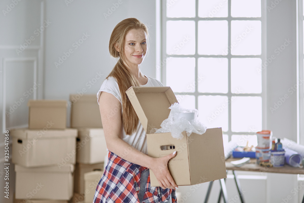 A beautiful single young woman unpacking boxes and moving into a new home A beautiful single young woman unpacking boxes and moving into a new home