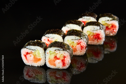 Traditional sushi roll with salmon, cream cheese, shrimp and cucumber on black stone. Japanese food