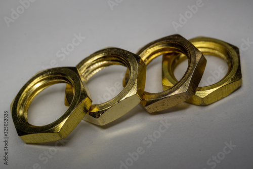 Close-up macro of four arranged gold hexagonal screw nuts isolated on white background