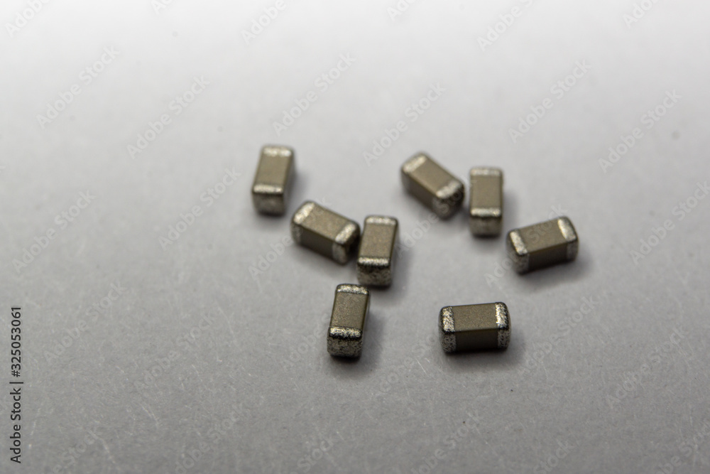 Abstract close-up of scattered 0603 SMT MLCC capacitors power electronics components white background in random pattern Abstract close-up of scattered 0603 SMT MLCC capacitors power electronics components white background in random pattern
