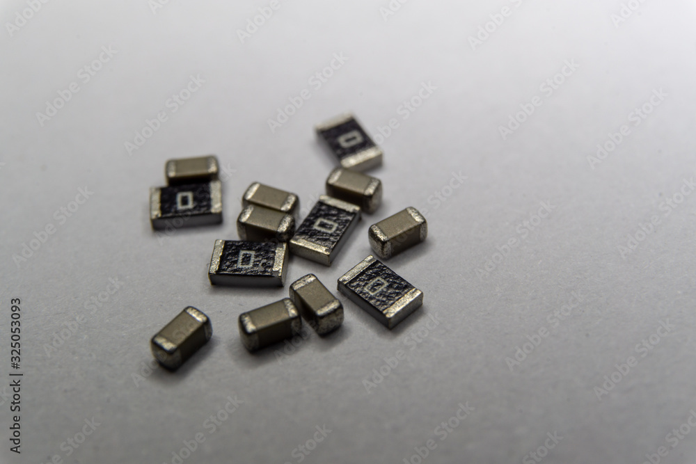 Abstract close-up scattered 0603 SMT MLCC capacitors, resistors electronics components white background random pattern Abstract close-up scattered 0603 SMT MLCC capacitors, resistors electronics components white background random pattern