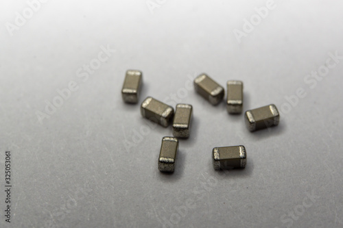 Abstract close-up of scattered 0603 SMT MLCC capacitors power electronics components white background in random pattern