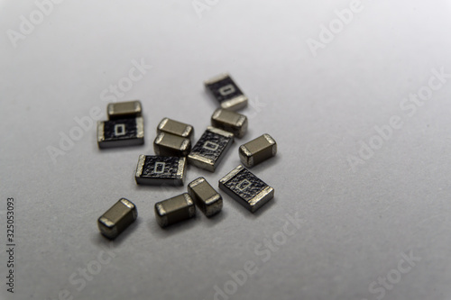 Abstract close-up scattered 0603 SMT MLCC capacitors, resistors electronics components white background random pattern photo