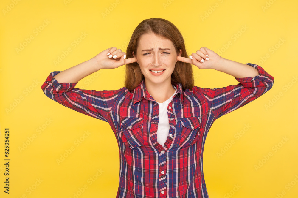 I don't want to hear! Portrait of irritated ginger girl in checkered shirt keeping ears closed not to listen loud annoying noise, high-decibel sound. indoor studio shot isolated on yellow background I don't want to hear! Portrait of irritated ginger girl in checkered shirt keeping ears closed not to listen loud annoying noise, high-decibel sound. indoor studio shot isolated on yellow background