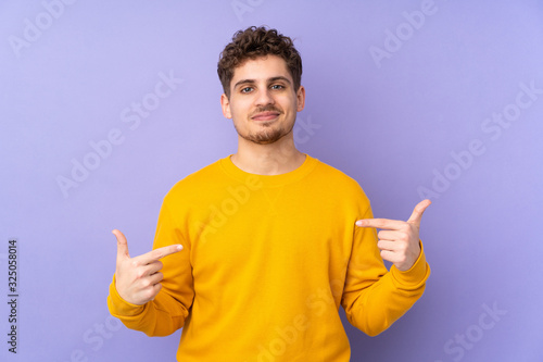 Caucasian man isolated on purple background proud and self-satisfied