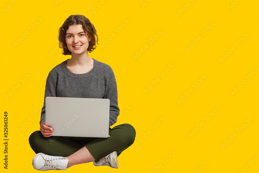 Naklejka premium Pretty Indian asian young girl using laptop computer isolated over yellow background