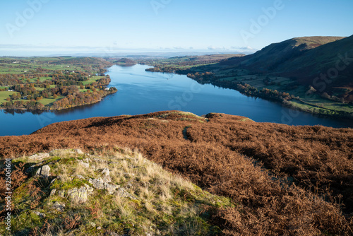 Beautiful Autumn Fall landscape of Ullswater and surrounding mountains and hills viewed from Hallin Fell on a crisp cold morning with majestic sunlgiht on the hillsides