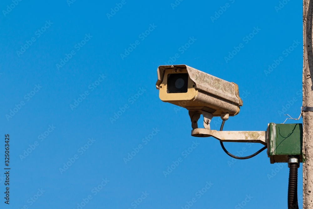Old security camera on the blue sky background Old security camera on the blue sky background