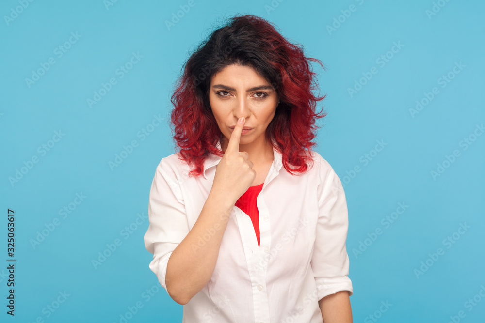 Falsehood sign. Portrait of angry displeased woman with fancy red hair in white shirt touching nose with lie gesture, blaming for deceit, forgery. indoor studio shot isolated on blue background Falsehood sign. Portrait of angry displeased woman with fancy red hair in white shirt touching nose with lie gesture, blaming for deceit, forgery. indoor studio shot isolated on blue background