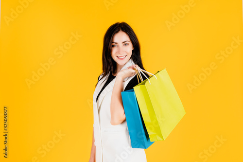 A young girl is carrying colorful shopping bags.