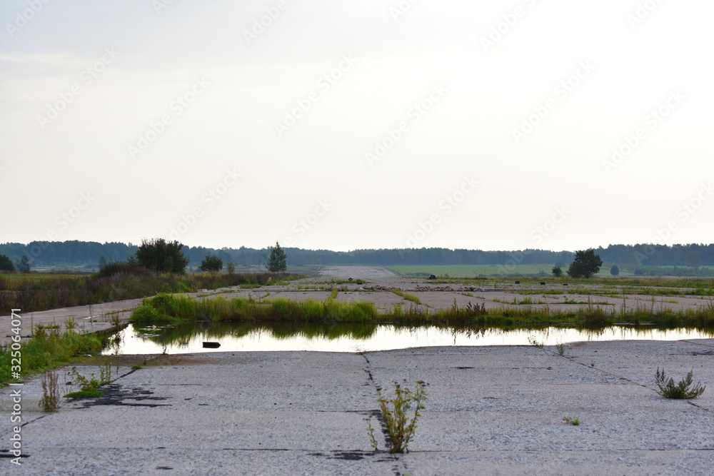 Old, abandoned, overgrown with grass airfield. Water puddle landscape Old, abandoned, overgrown with grass airfield. Water puddle landscape