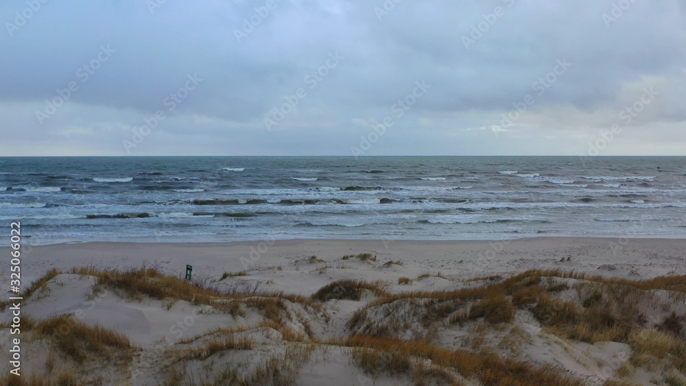Seascape of large waves and dunes and beach at overcast day Seascape of large waves and dunes and beach at overcast day