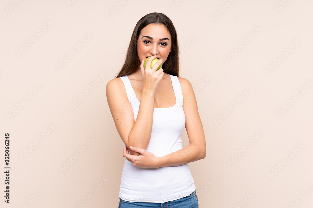 Young caucasian woman isolated on beige background eating an apple Young caucasian woman isolated on beige background eating an apple