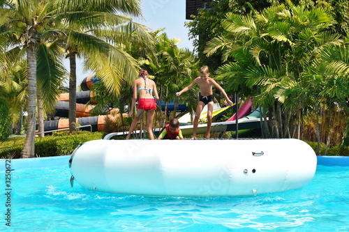 a water trampoline in the water Park. Funny kids on inflatable trampoline.