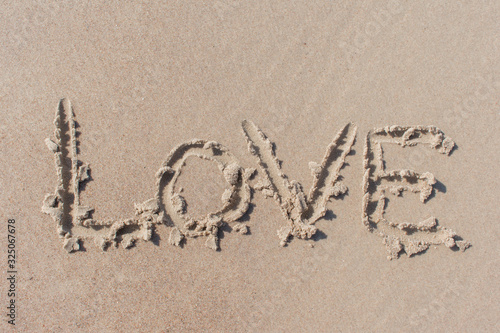 Text ''love'' written in beach sand © Abinieks