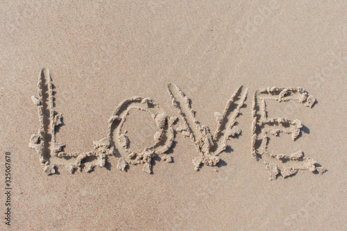 Text ''love'' written in beach sand