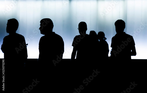 Silhouettes of people walking in the summer night in high contrast black and white