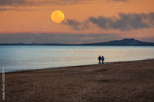 silhouette of couple on the beach under supermoon photo